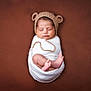 newborn, baby, sleeping, swaddled, hat, knitted_hat, bear_ears, infant, cute, peaceful, soft_background, brown_background, wrapped, toddler, portrait, tiny_toes, cozy, resting, studio_photo, child
