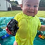 toddler, child, toy_car, yellow_swimsuit, water, pool, outdoor, grass, backyard, smile, happy, summer, sunlight, water_droplets, face, person, playing, plastic_pool, fun, daylight