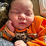 baby, sleeping, infant, orange_clothing, cute, peaceful, hand, face, resting, soft, closeup, portrait, newborn, child, skin, indoors, blanket, comfort, young, adorable