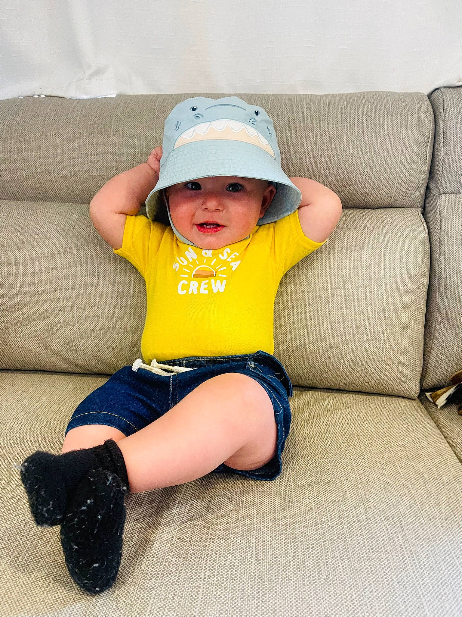 Jaxson is registered to the contest to win money with this photo: baby, baby_toddler_clothing, blue, cap, child, comfort, couch, electric_blue, foot, hat, headwear, human_leg, knee, person, product, shorts, sitting, sleeve, t_shirt, thigh