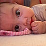 Flora is registered to the contest to win money with this photo: baby, infant, close_up, face, eyes, hand, lying_down, blanket, pink, tattoo, person, blue_hair, curious, soft_surface, indoor, casual_clothing, skin, portrait, child, cute