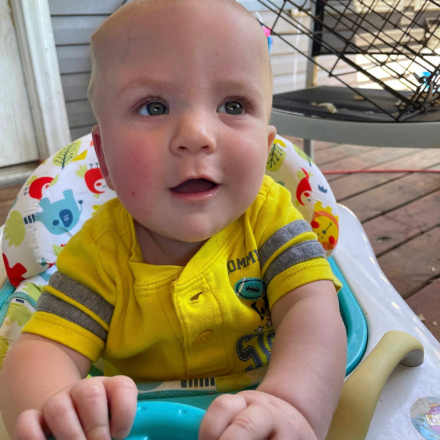 Earl joined the competition — help win amazing prizes! baby, baby_seat, child, colorful, curious, cute, face, furniture, hand, indoor, infant, pattern, person, playful, portrait, smiling, steering_wheel, toy, wooden_floor, yellow_shirt