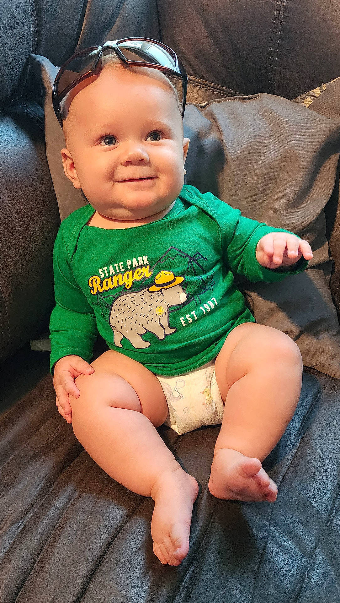 Alonso is registered to the contest to win money with this photo: accessories, baby, bodypart, clothing, couch, cushion, face, finger, furniture, glasses, hand, head, homedecor, person, photography, portrait, shorts, sitting, sunglasses, t_shirt