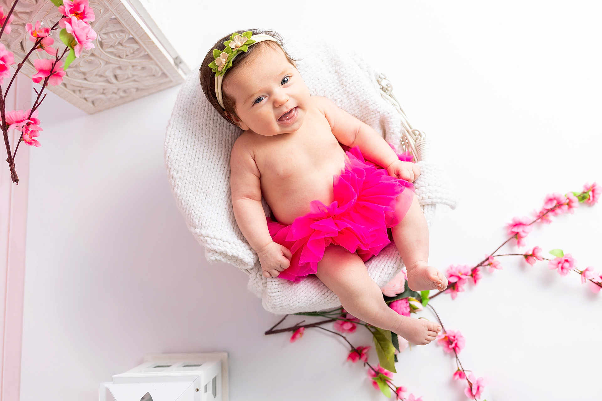 Lou-Anna a rejoint le concours — aidez-le/la à gagner de superbes lots ! baby, child, smiling, pink_tutu, headband, flower, knitted_blanket, white_chair, pink_flowers, portrait, cute, happy, infant, indoor, decor, soft_lighting, relaxed, skin, pretty, adorable