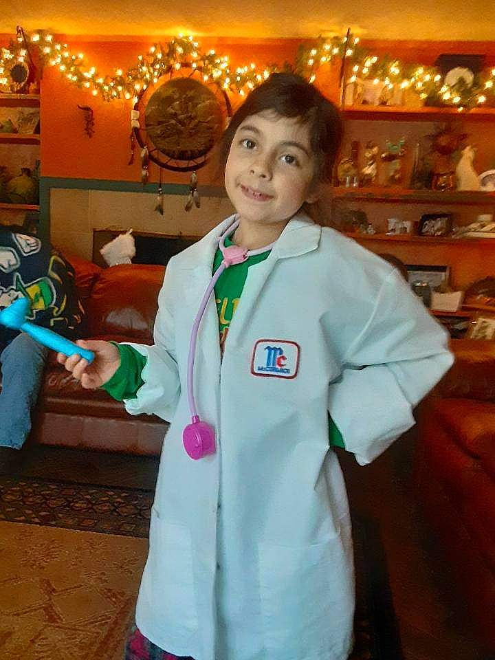 Isabella is registered to the contest to win money with this photo: child, costume, event, fun, happy, joy, person, recreation, room, shelf, sleeve, smile, thumb, uniform, white_coat