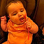 Isabella is registered to the contest to win money with this photo: baby, child, high_chair, orange_onesie, messy, spoon, food, feeding, cute, chubby, face, hand, clothing, infant, expression, sitting, indoors, young_child, meal_time, baby_food