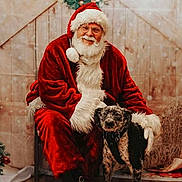 Remi is registered to the contest to win money with this photo: santa_claus, dog, christmas, holiday, wreath, red_suit, beard, glasses, black_boots, wooden_floor, chair, indoor, festive, decoration, pet, smiling, portrait, winter, fur, happy