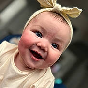 Alora joined the competition — help win amazing prizes! baby, blue_eyes, bokeh_background, bow, cheerful, close_up, cute, dimples, face, headband, headwear, indoor, infant, onesie, portrait, rosy_cheeks, shallow_depth_of_field, skin, smile, soft_lighting