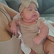 Carly joined the competition — help win amazing prizes! baby, infant, child, person, couch, indoor, clothing, headband, bow, arm, skin, cute, comfort, seated, holding, portrait, soft, cozy, expression, relaxed