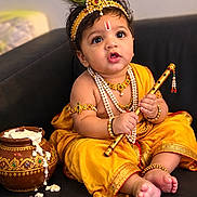 Gurbaaz is registered to the contest to win money with this photo: baby, barefoot, butter_pot, child, couch, flute, headpiece, indian_culture, indoor, infant, jewelry, musical_instrument, necklace, peacock_feather, portrait, sitting, smiling, traditional_clothing, wide_eyes, yellow_outfit