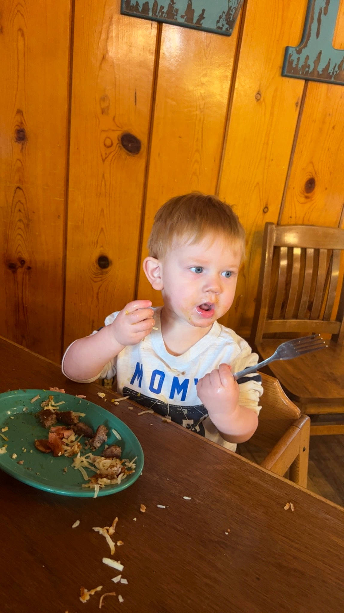 Sawyer is registered to the contest to win money with this photo: chair, child, comfort_food, cooking, cuisine, dish, dishware, eating, food, food_craving, fun, person, plate, recipe, sitting, surprise, t_shirt, table, tableware, toddler