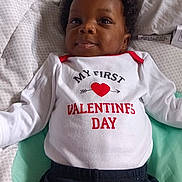 Zion is registered to the contest to win money with this photo: baby, infant, child, onesie, valentines_day, heart, bed, blanket, cute, smile, clothing, portrait, lying_down, indoors, soft, young_child, happy, face, head, cozy
