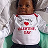 baby, infant, child, onesie, valentines_day, heart, bed, blanket, cute, smile, clothing, portrait, lying_down, indoors, soft, young_child, happy, face, head, cozy