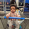 toddler, shopping_cart, child, adult, store_entrance, clothing, suspenders, bow_tie, sneakers, shopping, person, grocery, indoor, curly_hair, holding, retail, casual, wide_eyes, curious, evening