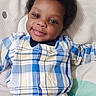 Zion joined the competition — help win amazing prizes! baby, child, smiling, plaid_shirt, white_pants, lying_down, cute, indoor, portrait, infant, happy, person, young_child, soft_surface, closeup, casual_clothing, adorable, face, eyes, hair