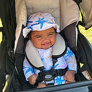 Brylee is registered to the contest to win money with this photo: baby, smiling, child, stroller, hat, starfish_pattern, outdoor, sunny, seatbelt, clothing, happy, infant, cute, babygear, headwear, person, portrait, babyface, sitting, babyclothes
