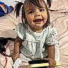 toddler, child, smiling, pigtails, bed, brush, charger, headphones, blanket, clothing, happy, indoor, person, cute, hair, sitting, toy, playful, young, face