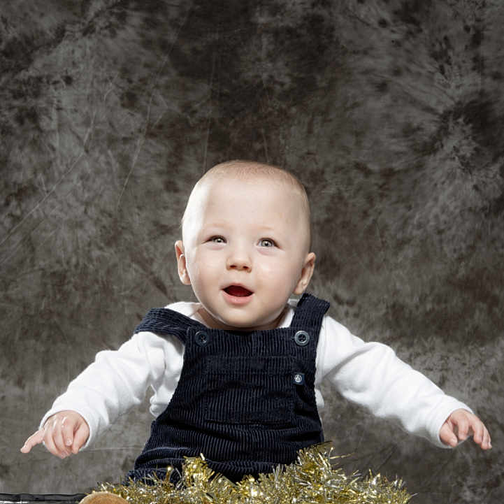 Raffaelu participe au concours pour gagner de l'argent avec cette photo : baby, background, child, curious, festive, floor, footwear, happy, holiday_decor, indoor, overalls, person, photography, portrait, sitting, smiling, studio, tinsel, white_shirt, young_child