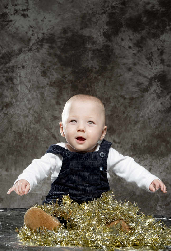Raffaelu participe au concours pour gagner de l'argent avec cette photo : baby, background, child, curious, festive, floor, footwear, happy, holiday_decor, indoor, overalls, person, photography, portrait, sitting, smiling, studio, tinsel, white_shirt, young_child