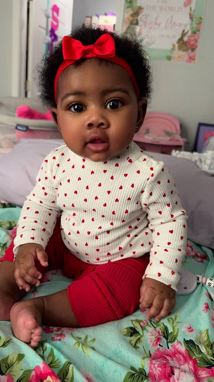 Skylar joined the competition — help win amazing prizes! accessories, baby, bed, bedroom, bodypart, clothing, couch, cushion, face, furniture, head, homedecor, indoors, person, photoframe, photography, portrait, room, shorts, sitting