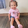 Bella is registered to the contest to win money with this photo: toddler, child, smiling, sitting, hair_clips, pink_shoes, shorts, tshirt, wooden_floor, curtain, indoor, happy, cute, person, portrait, casual_clothing, light_wall, flooring, young_child, playful