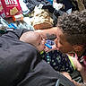 baby, blanket, casual, cheese_bits, child, close_up, clothes, clothing, curly_hair, cute, family, indoor, infant, interaction, lying_down, person, snack_box, tattoo, teething_toy, toy