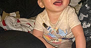 Carson joined the competition — help win amazing prizes! baby, blanket, blue_eyes, child, clothing, comfort, cozy, cute, face, happy, home, indoor, infant, person, pillow, playful, sitting, smile, toddler, young