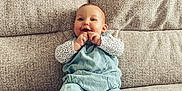 Phoebe is registered to the contest to win money with this photo: baby, child, infant, couch, sofa, blue_overalls, happy, smiling, barefoot, indoor, person, seated, cozy, cute, fingers, face, foot, comfortable, home, portrait