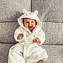 Phoebe joined the competition — help win amazing prizes! baby, child, smiling, hooded_robe, white_clothing, sitting, couch, furniture, happy, cute, indoors, portrait, cozy, plush, infant, face, expression, soft, warm, comfortable