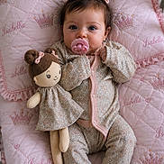Isabella is registered to the contest to win money with this photo: baby, child, pacifier, pigtails, doll, pink, blanket, quilted, embroidery, clothing, infant, cute, indoor, portrait, soft_lighting, toy, bed, comfort, person, sleepwear