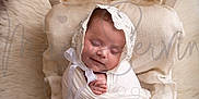 Ailany is registered to the contest to win money with this photo: baby, sleeping, wrapped, white_cloth, lace_bonnet, woven_bed, fluffy_rug, cream_color, peaceful, newborn, infant, portrait, cozy, soft_texture, cute, child, resting, indoors, head, hands