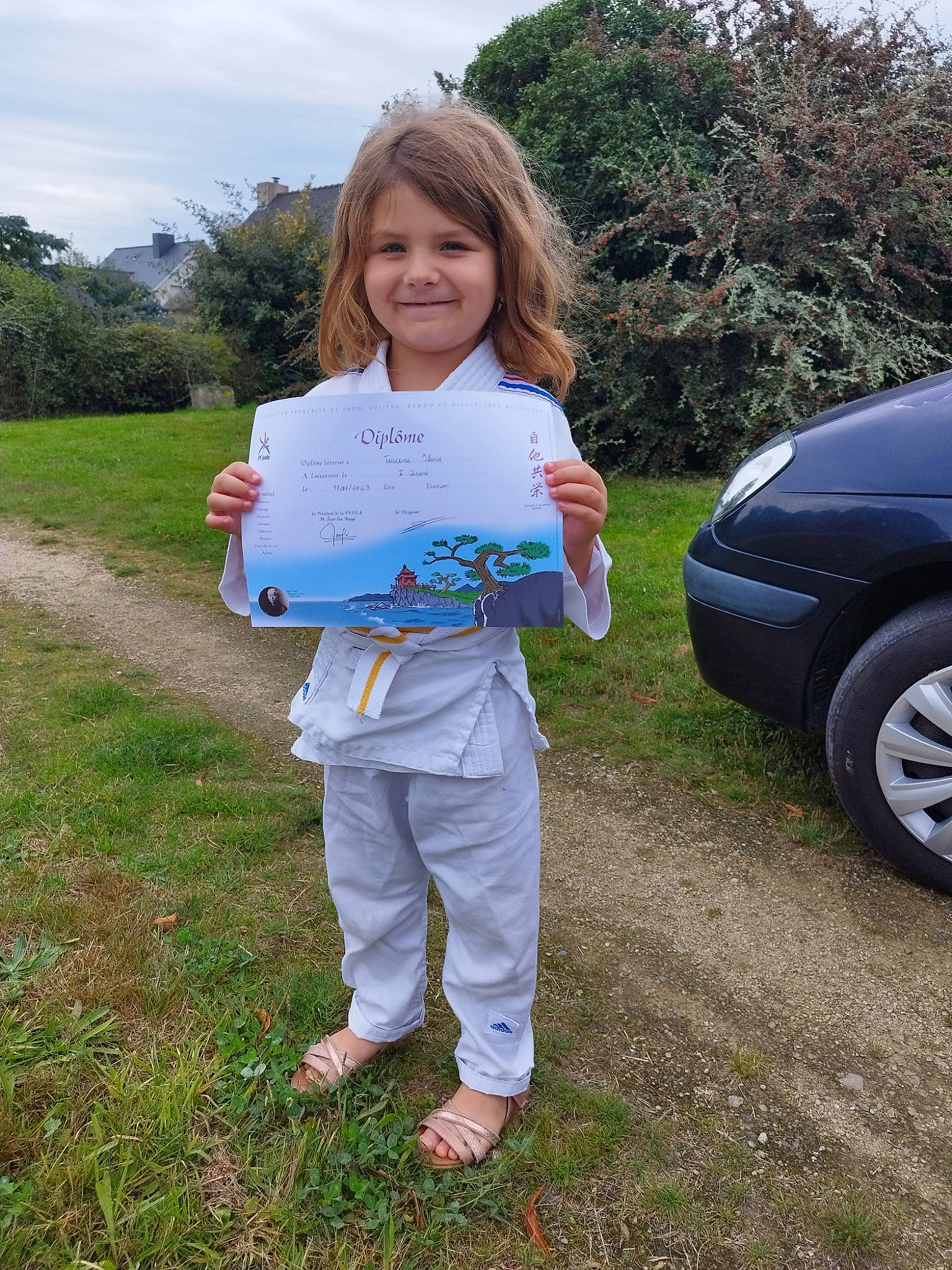 Ilana a rejoint le concours — aidez-le/la à gagner de superbes lots ! alloy_wheel, automotive_design, automotive_exterior, automotive_lighting, automotive_tire, bumper, car, grass, hood, joy, motor_vehicle, person, plant, recreation, rim, sky, smile, tire, tree, vehicle