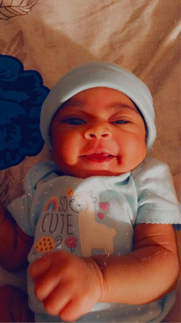 Genesis is registered to the contest to win money with this photo: baby, baby_toddler_clothing, cap, cheek, chin, eyebrow, face, facial_expression, finger, happy, hat, headwear, iris, lip, mouth, nose, person, pink, skin, sleeve