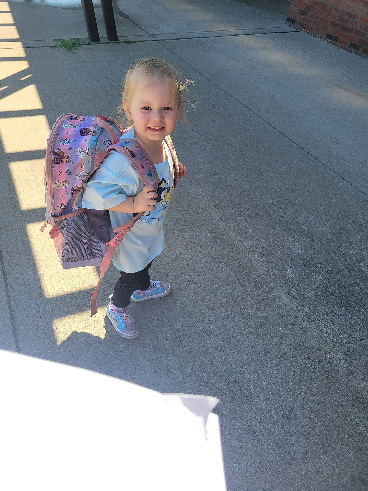 Charlotte is registered to the contest to win money with this photo: accessories, backpack, bag, child, clothing, coat, face, female, footwear, girl, handbag, head, pants, person, photography, road, shoe, sneaker, strap, walking