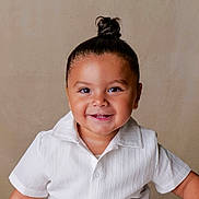 Mohamed a rejoint le concours — aidez-le/la à gagner de superbes lots ! toddler, child, smile, happy, face, hair_bun, white_shirt, portrait, studio, cute, young_child, innocence, person, human, baby_teeth, short_sleeves, light_background, skin, eyebrows, eyes