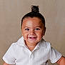 toddler, child, smile, happy, face, hair_bun, white_shirt, portrait, studio, cute, young_child, innocence, person, human, baby_teeth, short_sleeves, light_background, skin, eyebrows, eyes