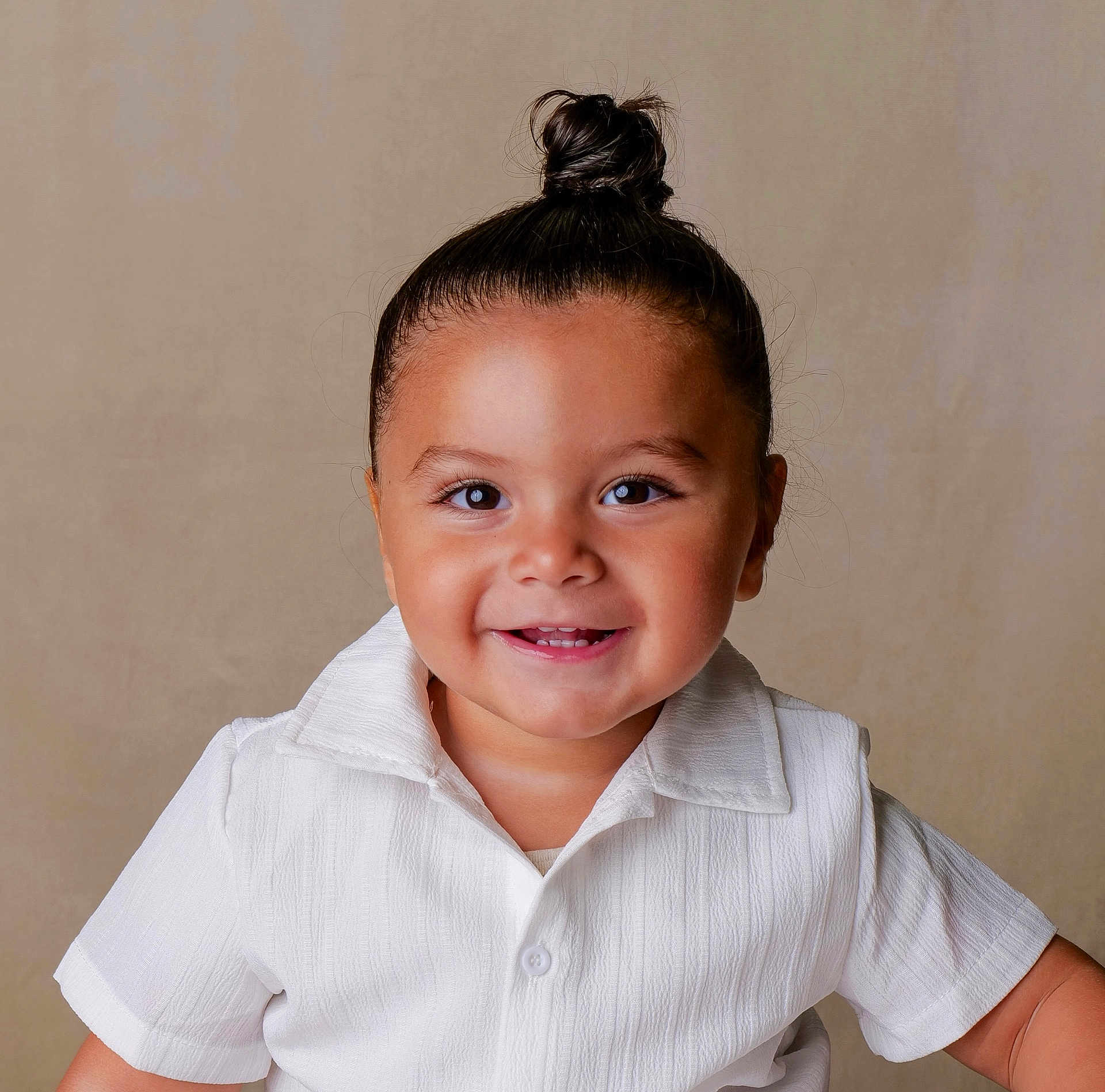 Mohamed a rejoint le concours — aidez-le/la à gagner de superbes lots ! toddler, child, smile, happy, face, hair_bun, white_shirt, portrait, studio, cute, young_child, innocence, person, human, baby_teeth, short_sleeves, light_background, skin, eyebrows, eyes