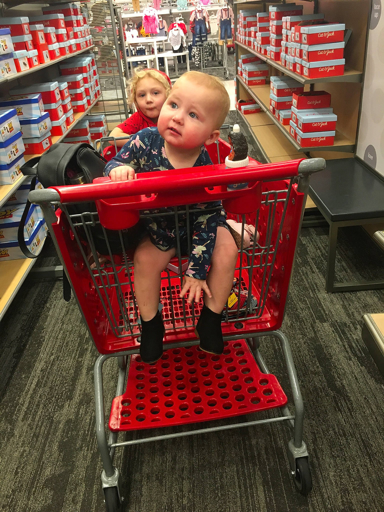 Jackie is registered to the contest to win money with this photo: cart, child, convenience_store, customer, flooring, fun, grocery_store, human_leg, leg, person, product, publication, red, retail, service, shelf, shelving, shopping, shopping_cart, sitting