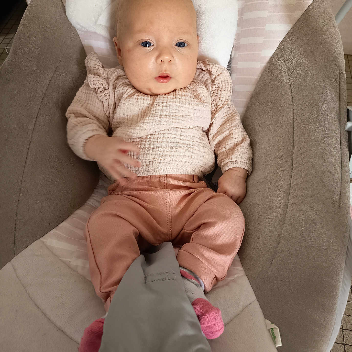 Mëlyne a rejoint le concours — aidez-le/la à gagner de superbes lots ! baby, baby_seat, bouncer, child, cute, eyes, face, gaze, hand_motion, headrest, indoor, infant, mouth, padded_cushion, peach_pants, pink_clothes, pink_sock, plush_toy, portrait, tile_floor