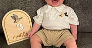Maverick joined the competition — help win amazing prizes! baby, barefoot, child, collar, couch, happy, home, indoor, infant, milestone, photography, plaque, portrait, shirt, shorts, sitting, smiling, sofa, three_months, wooden_sign