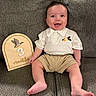 baby, child, infant, smiling, happy, portrait, sitting, sofa, couch, milestone, three_months, plaque, wooden_sign, barefoot, shorts, shirt, collar, indoor, home, photography