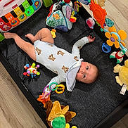 Maverick joined the competition — help win amazing prizes! baby, infant, child, playpen, toys, plush_toys, rattle, musical_toy, activity_gym, onesie, lying_down, smiling, face, indoor, portrait, colorful, playtime, nursery, stuffed_animal, safe
