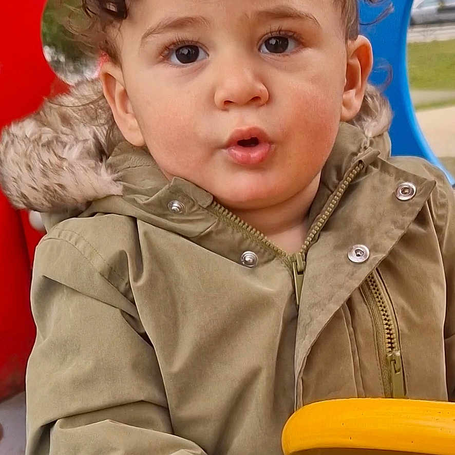 Ayden participe au concours pour gagner de l'argent avec cette photo : baby, bodypart, clothing, coat, face, finger, grass, hand, head, jacket, nature, outdoorplayarea, outdoors, park, person, photography, plant, playarea, portrait, toy