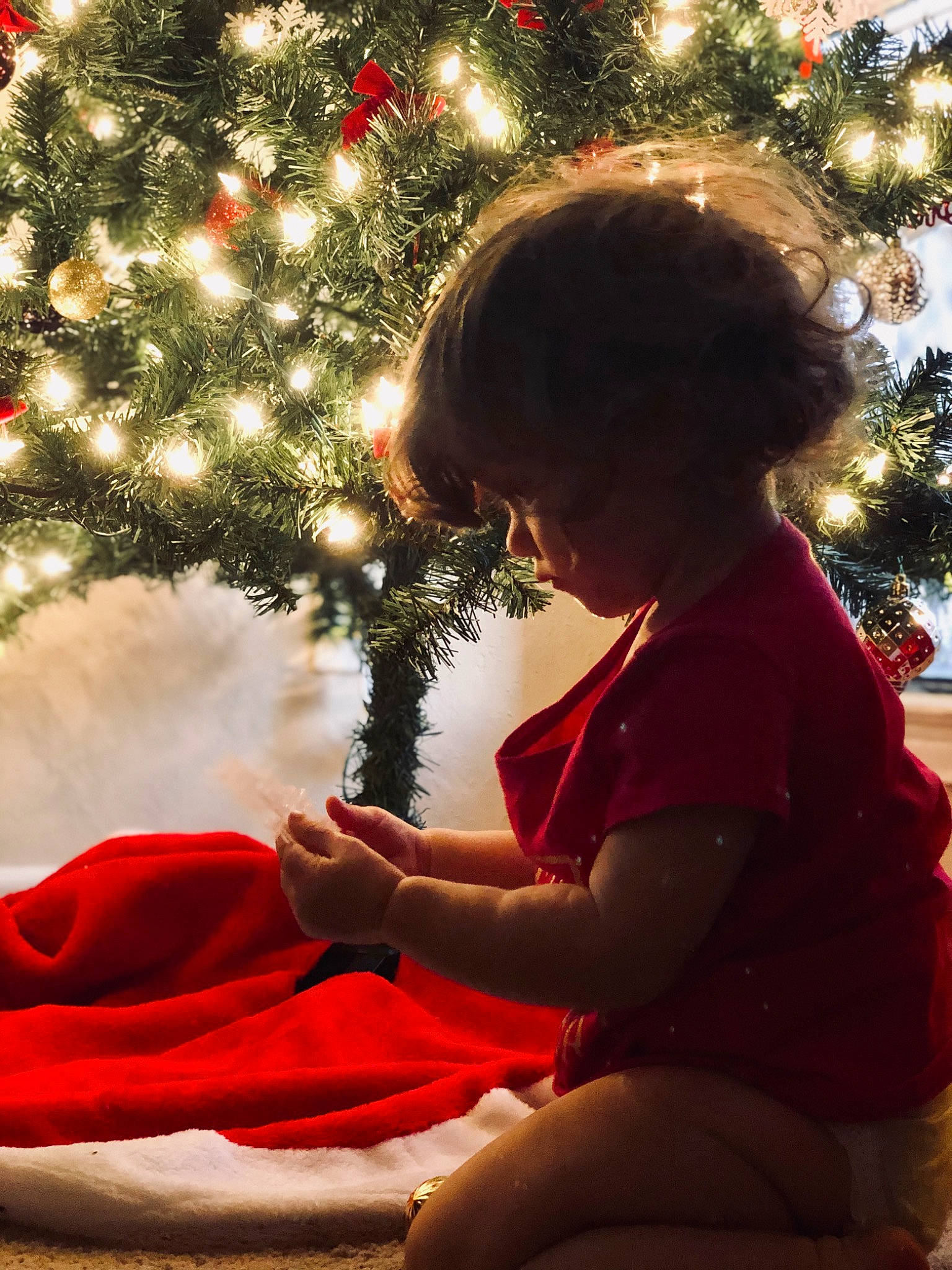 Riley Claire is registered to the contest to win money with this photo: child, christmas, christmas_decoration, christmas_eve, christmas_lights, christmas_ornament, christmas_tree, conifer, event, fir, holiday, interior_design, person, pine_family, plant, sitting, spruce, toddler, tradition, tree