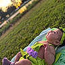 Meredith is registered to the contest to win money with this photo: baby, infant, child, grass, outdoor, sunset, blanket, green_clothing, purple_flowers, headband, socks, nature, sunlight, portrait, cute, lying_down, happy, young_child, playful, scenic_background