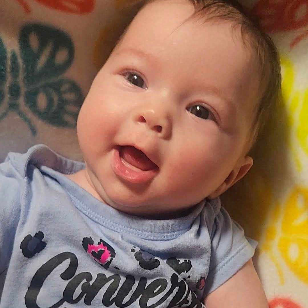 Charlee is registered to the contest to win money with this photo: baby, smiling, face, child, infant, clothing, tshirt, pattern, text, converse, leopard_print, blanket, butterfly, colorful, happy, cute, portrait, young, skin, person