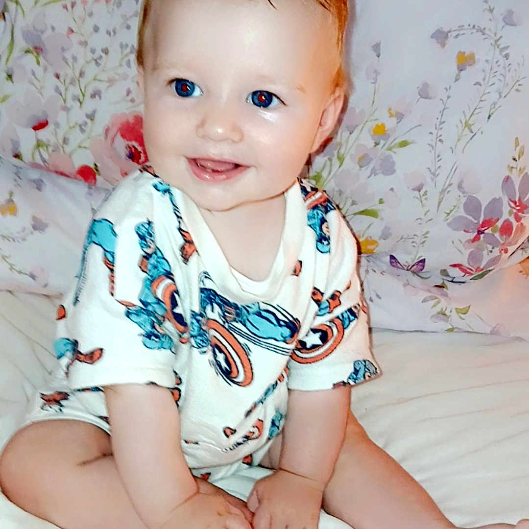 Jacob is registered to the contest to win money with this photo: baby, bed, bedroom, clothing, crawling, cushion, dress, face, furniture, happy, head, homedecor, indoors, person, photography, portrait, room, sitting, smile, t_shirt