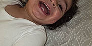 Chalom participe au concours pour gagner de l'argent avec cette photo : bed, bedspread, child, expression, face, hair, happy, indoor, joy, lying_down, mouth_open, pattern, person, portrait, skin, smiling, teeth, toddler, white_clothing, young_child