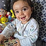 Chalom a rejoint le concours — aidez-le/la à gagner de superbes lots ! baby, book, child, clothing, couch, cozy, cute, eyes, face, hand, happy, indoors, long_hair, patterned_cushion, playtime, plush_toys, reading, seated, smiling, toddler