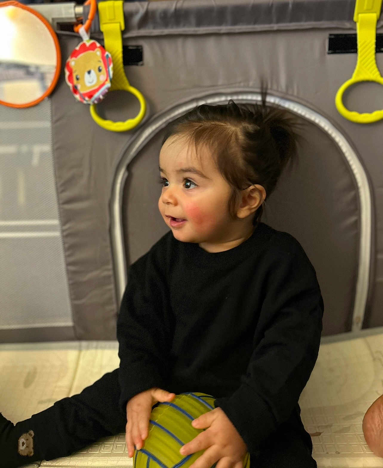 Chalom a rejoint le concours — aidez-le/la à gagner de superbes lots ! baby, baby_toy, ball, black_clothing, child, colorful, curly_hair, cute, face, hand, happy, indoor, playmat, playpen, portrait, sitting, smiling, toddler, toy, young_child